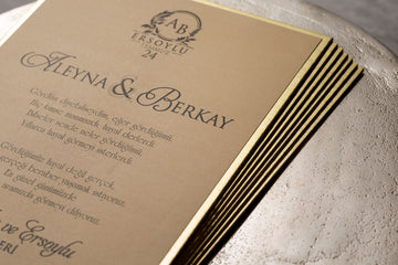 Elegant gold-edged wedding invitations with script text on beige cardstock, close-up view