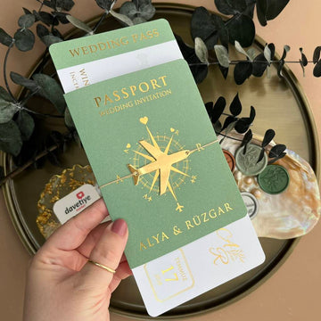 Green passport-style wedding invitation with gold airplane design and elegant detailing.